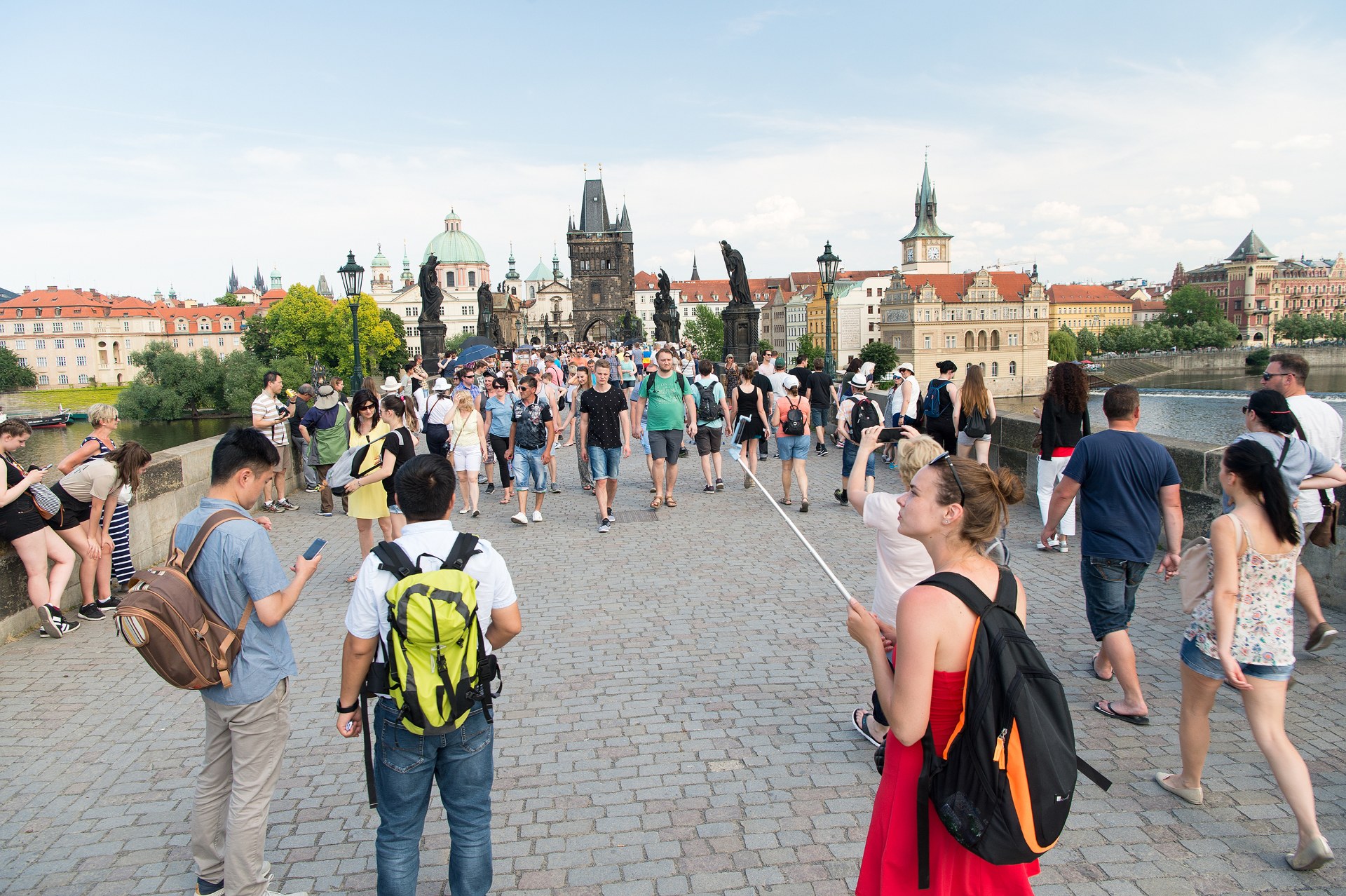 Jeunes avec des sacs à dos traversant le pont Charles à Prague, avec la tour du pont de la Vieille Ville en arrière-plan